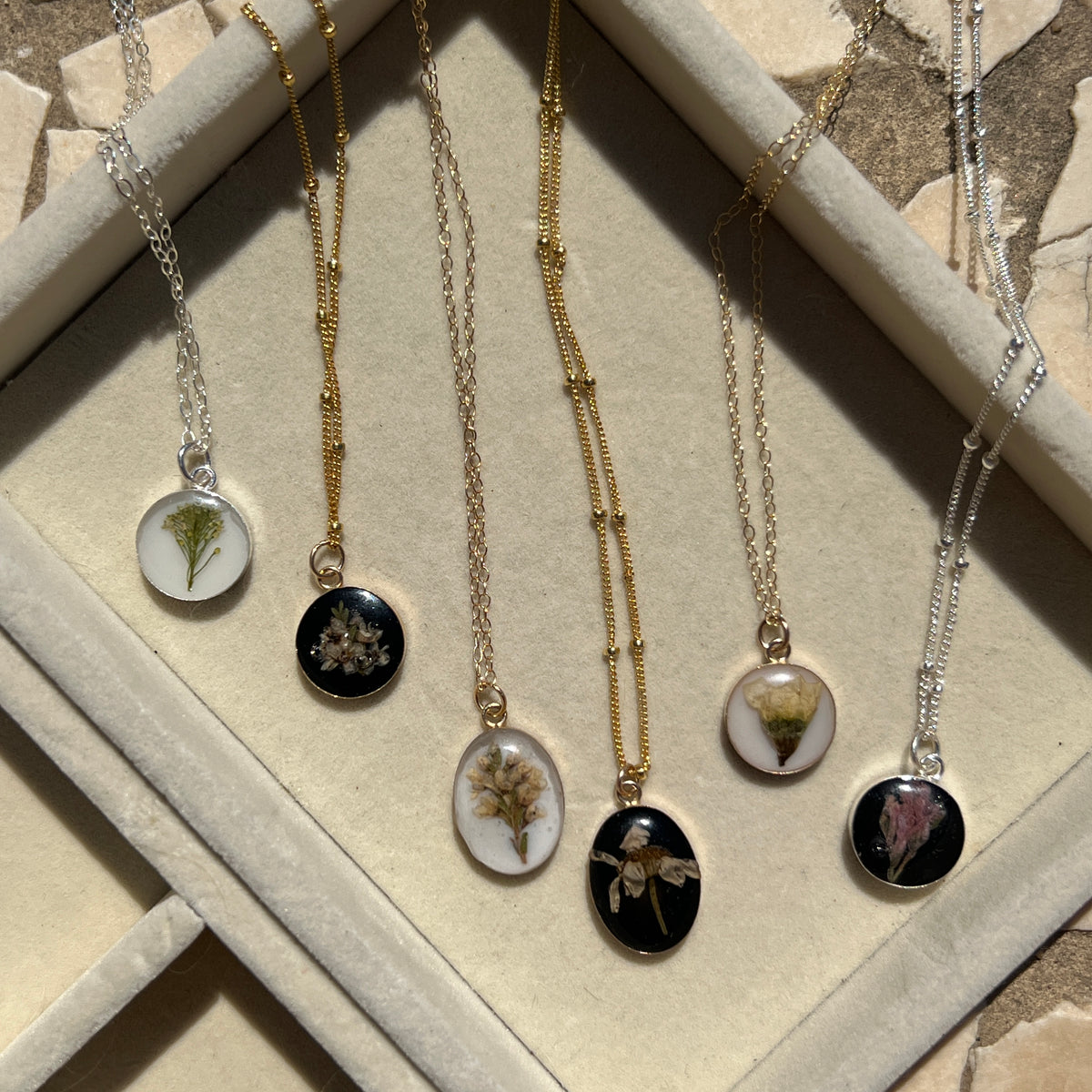 Sterling silver pendant necklace in round and oval shapes featuring preserved flowers, handcrafted by Happihome as a delicate floral keepsake.