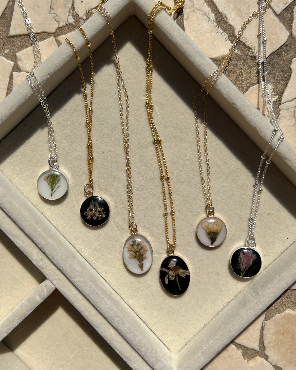 Sterling silver pendant necklace in round and oval shapes featuring preserved flowers, handcrafted by Happihome as a delicate floral keepsake.