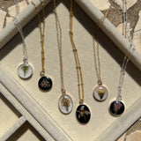 Sterling silver pendant necklace in round and oval shapes featuring preserved flowers, handcrafted by Happihome as a delicate floral keepsake.